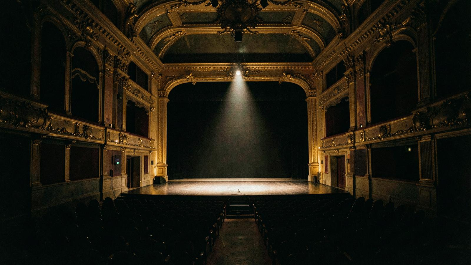 Empty concert hall lit by a single stage light.